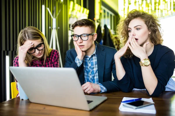 Three upset friends online using a laptop with problems and sad emotions in a coffee shop — Stock Photo, Image