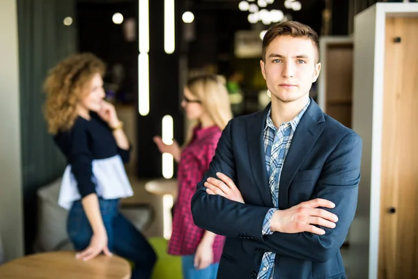 Joven frente a sus compañeros de trabajo con las manos cruzadas en la oficina moderna . — Foto de Stock