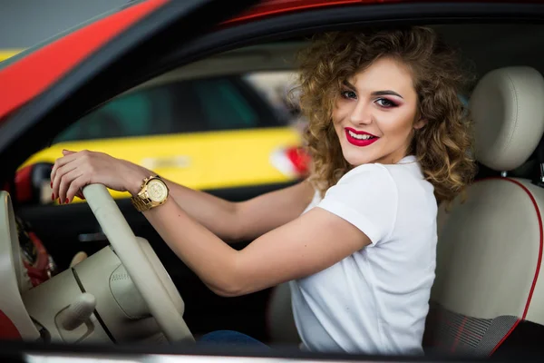 Mooie jonge vrouw haar nieuwe auto rijden en kijk naar de camera vanuit venster — Stockfoto