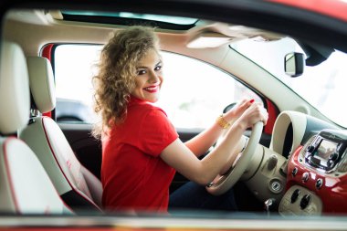 Şehir etrafında sürüş. Gülümseyen ve bir araba sürüş sırasında düz görünümlü genç çekici kadın