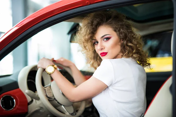 Vista trasera de la atractiva joven en ropa casual mirando por encima de su hombro mientras conduce un coche — Foto de Stock