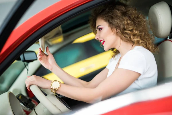 Zijaanzicht van leuke stijlvolle meisje aanraken een achteruitkijkspiegel en glimlachen tijdens het rijden de auto — Stockfoto