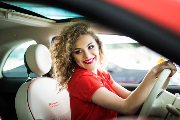 Rijden rond de stad. Jonge aantrekkelijke vrouw lachend en rechte kijken tijdens het rijden van een auto — Stockfoto