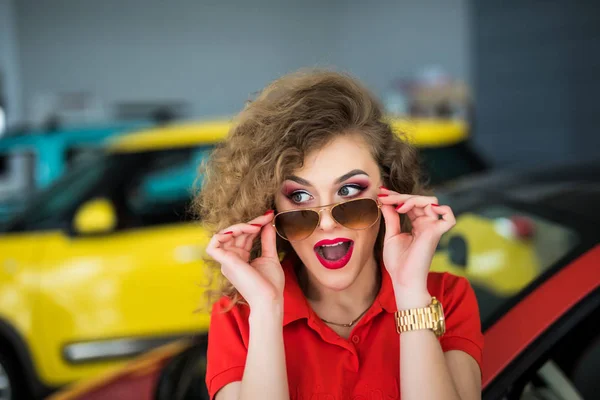 Mooi meisje op in de omgeving van auto in dealer verkoper — Stockfoto