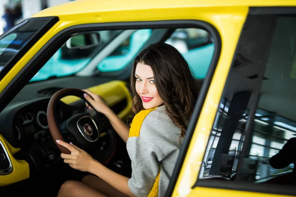 Mooie Smiling vrouw rijden gele auto, aantrekkelijk meisje zit in de auto, portret. — Stockfoto