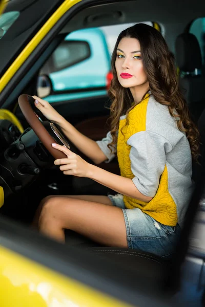 Красива усміхнена жінка за кермом жовтого автомобіля, приваблива дівчина сидить в автомобілі, портрет . — стокове фото