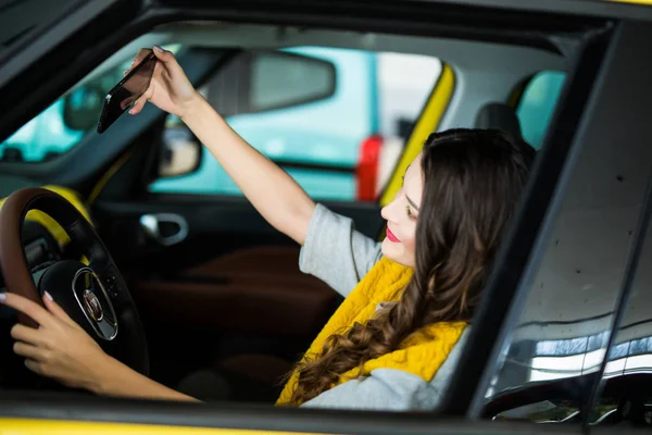 Lachende jonge vrouw nemen selfie foto met slimme telefooncamera in de auto — Stockfoto