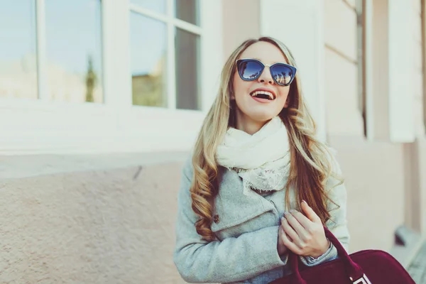 행복 하 고 밝고, 선글라스 젊은 모델 또는 밖에 서 자연 거리 배경에 빛 코트에 학생에 금발을 웃 고. — 스톡 사진