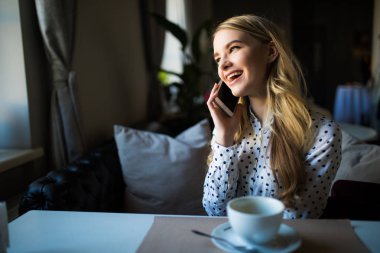 Genç erkek arkadaşıyla kafede dinlenirken mobil akıllı telefonda konuşurken iyi bir ruh hali ile güzel