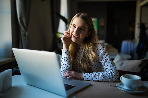 Mujer joven usando computadora portátil. Mujer trabajando en un ordenador portátil en una cafetería al aire libre . — Foto de Stock