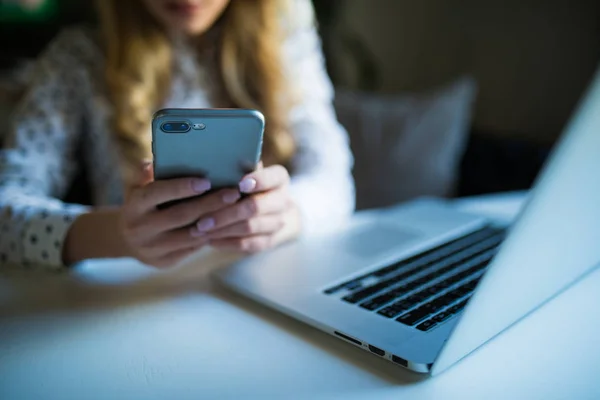 Bijgesneden shot van een vrouw in café werken met telefoon in handen op haar laptopcomputer. — Stockfoto