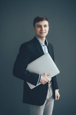 Adam elinde dizüstü bilgisayar ile koyu arka plan üzerinde ayakta