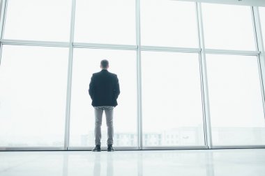 Büyük bir pencerenin arkasında şık bir iş adamı