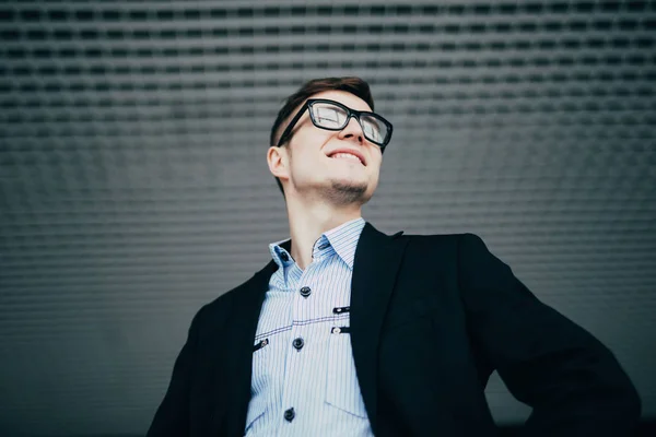 Uśmiechający się młody biznesmen, noszenie okularów ścianę z bliska — Zdjęcie stockowe