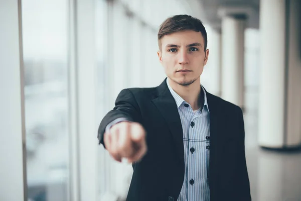 Joven hombre de negocios en un traje señalando con su dedo oficina — Foto de Stock