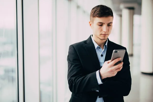 Pohled na mladou atraktivní obchodní člověka pomocí smartphone v kanceláři — Stock fotografie