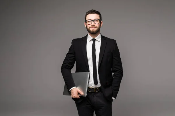 Όμορφος επιχείρηση άνθρωπος γυαλιά και κοστούμι κρατώντας το laptop στα χέρια πλευρά άποψη απομονωμένη γκρι φόντο — Φωτογραφία Αρχείου