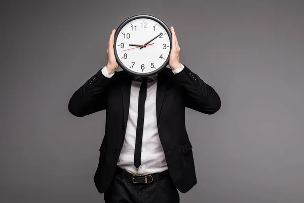 Uomo in tuta grigia con grande orologio che si copre il viso — Foto Stock