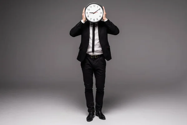 Piena altezza bell'uomo in tuta grigia che tiene grande orologio che si copre il viso — Foto Stock