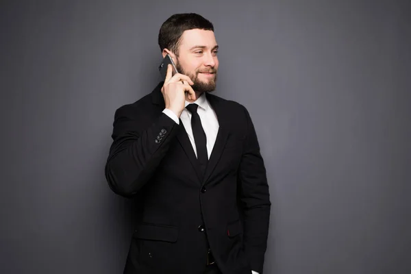 Elegáns üzletember egy komoly beszélgetést egy okos telefon, egy sötét háttér — Stock Fotó