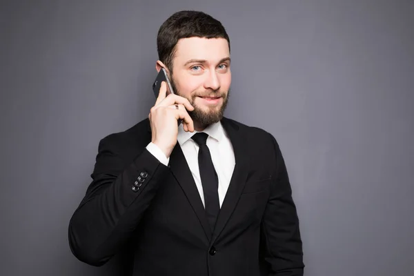 Elegáns üzletember egy komoly beszélgetést egy okos telefon, egy sötét háttér — Stock Fotó