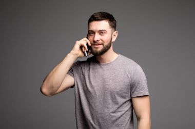 Kullanım telefon, yakışıklı genç gömlek biliyor cep telefonu gri arka plan karşı dururken