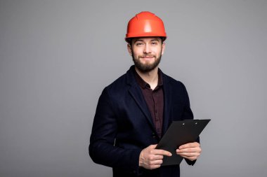 Yanındaki için bakmak ve siyah klasör tutan bir siyah takım elbise ve inşaat kask içinde adam