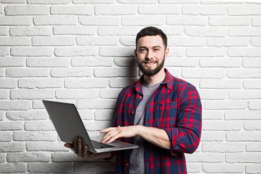 Modern dizüstü bilgisayar kullanan mutlu genç adam