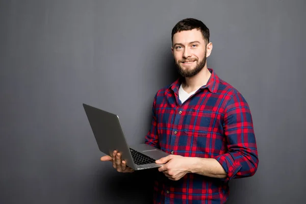 Hombre casual guapo mostrando pantalla portátil en blanco sobre fondo gris . —  Fotos de Stock