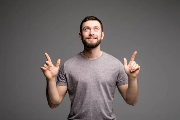 Feliz joven alegre haciendo gestos con los dedos en gris —  Fotos de Stock