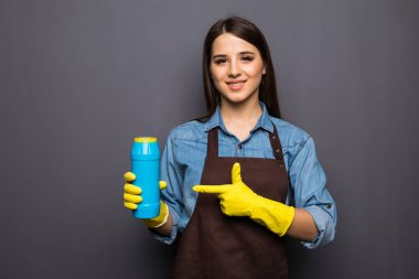 Genç ev hanımı gri backgroung üzerinde elinde deterjanlar ile Temizleme