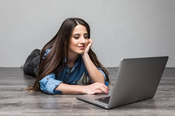 Leende kvinna som arbetar på laptop på golvet — Stockfoto