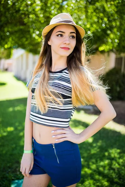 Mulher morena jovem bonita com cabelos longos voando no vento e chapéu marrom no parque no verão . — Fotografia de Stock