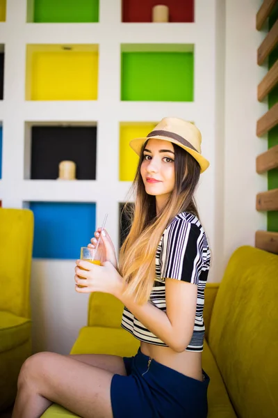 Mulher bonita com copo de suco de fruta fresca usando chapéu no café — Fotografia de Stock