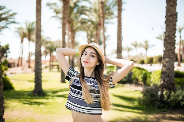 Heureuse jeune femme en vêtements d'été et chapeau de soleil à la station balnéaire — Photo