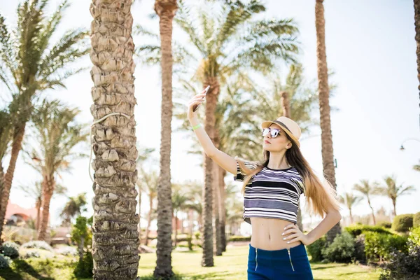 Jeune femme prenant selfie avec smartphone sur fond de palmiers d'été. vocation estivale , — Photo