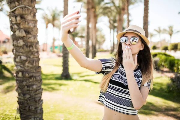 Femme prendre selfie au téléphone sur les paumes et envoyer des baisers milieux. Concept de vocation estivale . — Photo