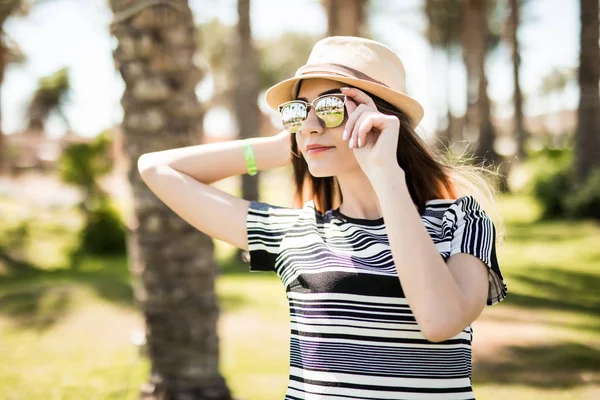 Joyeux jeune femme en chapeau et lunettes de soleil dans les fonds de palmiers d'été. vocation estivale . — Photo