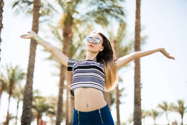 Mujer joven con las manos levantadas en el complejo con fondo de palmas. Vocación de verano —  Fotos de Stock