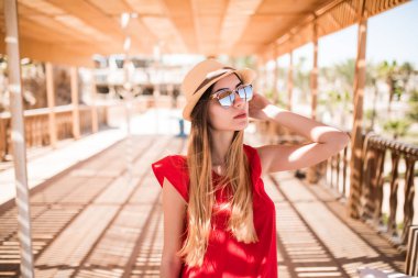 Genç kız bir kırmızı güneş elbise ve şapka iskelede ayakta beyaz. Yaz meslek