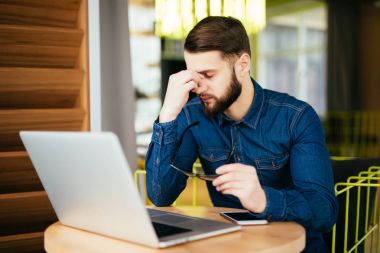 Office çalışma evinde otururken masaj onun burun ve gözler tutmak hayal kırıklığına uğramış genç sakallı adam kapalı