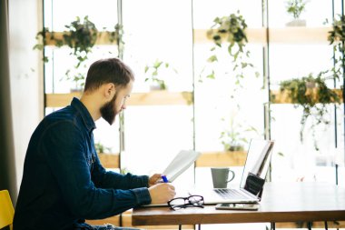 Hatta bir dizüstü bilgisayar ile çalışma ve modern bir ofis belgeleri tutan serbest adam