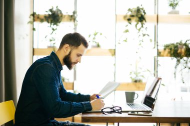 Hatta bir dizüstü bilgisayar ile çalışma ve modern bir ofis belgeleri tutan serbest adam