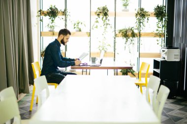 Hatta bir dizüstü bilgisayar ile çalışma ve modern bir ofis belgeleri tutan serbest adam