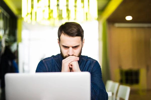 Retrato del hombre pensante usando computadora portátil en la cafetería — Foto de Stock