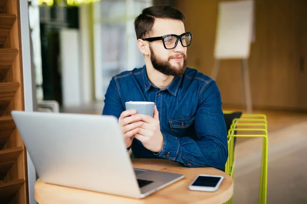 Retrato del hombre de negocios sonriente leyendo el mensaje con el teléfono inteligente en la oficina . — Foto de Stock