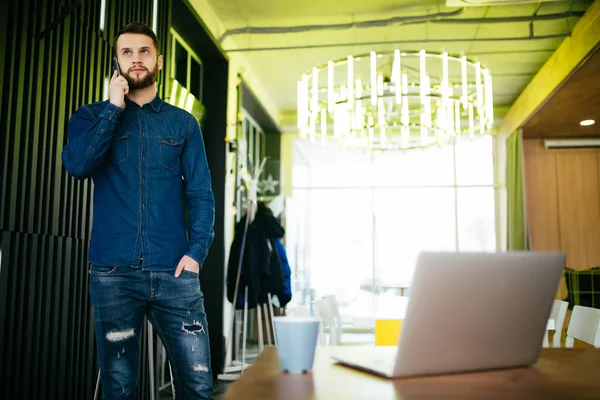 Masasında duran ve Ofis telefonu konuşurken yakışıklı erkek girişimci — Stok fotoğraf