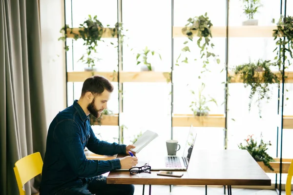 Hatta bir dizüstü bilgisayar ile çalışma ve modern bir ofis belgeleri tutan serbest adam