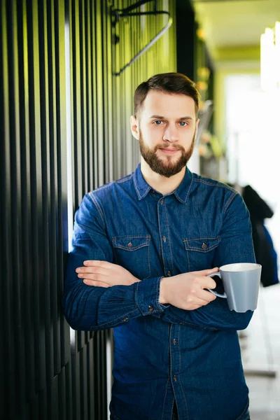 Yakışıklı adam rahat bir fincan tutarak ve uzak duran ofisinde arıyor — Stok fotoğraf