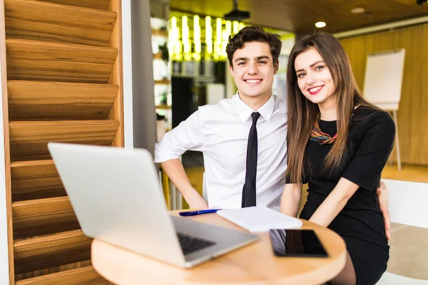 Joven equipo de negocios trabajando juntos en un ordenador portátil sonriendo mientras ven su proyecto llegar a buen término, hombre y mujer — Foto de Stock